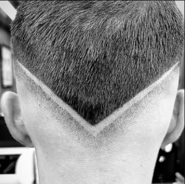 Hair tattoo en V afeitado en la nuca sobre fade bajo